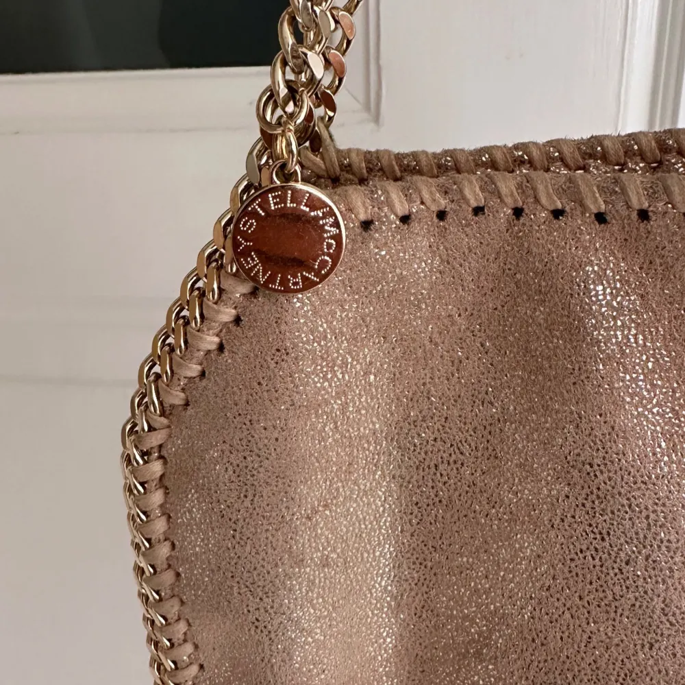 Snygg beige/rosa från Stella McCartney i mycket bra skick. Väskan har en glittrig yta och kedjedetaljer i guld. Modellen falabella. Kommer inte sälja under 5000 så ni vet då den är i väldigt fint skick! . Väskor.