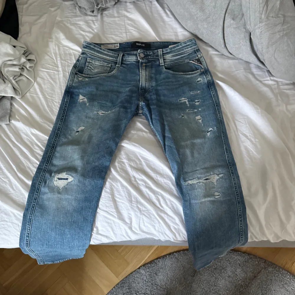 Säljer ett par snygga blå jeans från Replay i bra skick. De har en cool slitningseffekt och en klassisk femficksdesign. Perfekta för en avslappnad stil. Passar både till vardags och fest! 30/30. Jeans & Byxor.