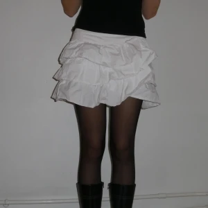 Vit volangkjol - Superfin vit minikjol med volanger. Lowwaisted. Storlek S (ca strlk 36/38). Liten dragkedja på ena sidan för att stänga den. 