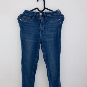Blå jeansbyxor - Säljer ett par klassiska blå jeansbyxor i bra skick. De har en snygg skinny passform och är perfekta för både vardag och fest. Byxorna har en knapp och dragkedja framtill samt fickor både fram och bak. Perfekta för alla säsonger!