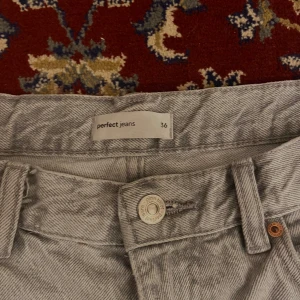 Grå jeans från Perfect Jeans - Säljer ett par snygga grå jeans från Perfect Jeans i storlek 36. De har en klassisk design med knapp och dragkedja framtill. Perfekta för både vardag och fest! 🖤