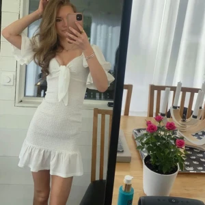 Vit sommarklänning med volanger - Säljer min avslutningsklänning, använd typ en gång och är i fint skick den är jätte fin till sommaren men ja säljer då jag själv inte använder den mer