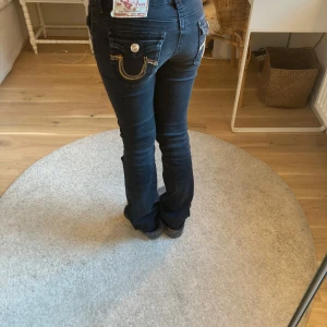 Svarta True religion jeans - Säljer ett par snygga svarta true religion jeans. Dom är lågmidjade och bootcut. Dom är i storlek 25!❤️💛🖤