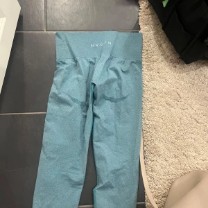 Blå leggings från NVGTN - Säljer ett par snygga blå leggings från NVGTN. De är perfekta för träning och har en tight passform som framhäver figuren. Materialet är mjukt och stretchigt, vilket gör dem bekväma att bära under långa träningspass. Perfekta för både gymmet och yoga!