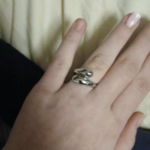 Silverfärgad ring - Snygg och modern silverfärgad ring med en unik, böjd design. Perfekt för att ge en stilren touch till vilken outfit som helst. Passar både till vardags och festliga tillfällen.