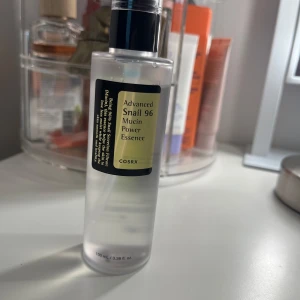 COSRX Advanced Snail 96 Mucin Power Essence - Säljer en flaska COSRX Advanced Snail 96 Mucin Power Essence. Den innehåller 100 ml och är perfekt för att återfukta och ge näring till huden. Flaskan är genomskinlig med en svart pump och etikett. Perfekt för dig som vill ha en mjuk och strålande hy! Endast testat ett par gånger