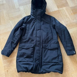 Svart parkajacka från McKinley - Säljer en svart parkajacka från McKinley i storlek 42. Jackan har en praktisk huva och långa ärmar, perfekt för kyliga dagar. Den är i mycket bra skick och har stora fickor framtill. Perfekt för höst- och vinteräventyr!