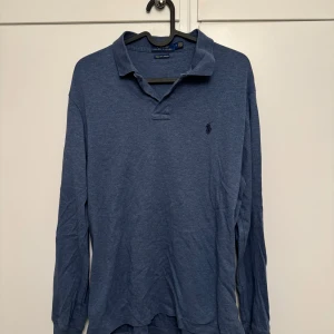 Blå pikétröja från Ralph Lauren - Säljer en snygg blå pikétröja från Ralph Lauren i storlek M. Tröjan är långärmad och har en klassisk krage. Perfekt för både vardag och lite finare tillfällen. Den är i bra skick och supermjuk tack vare 'Pima Soft Touch'-materialet.