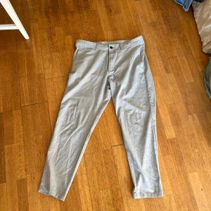 Grå kostymbyxor från Zara - Säljer ett par stilrena grå kostymbyxor från Zara i storlek 34. Byxorna har en klassisk straight passform med knapp och dragkedja framtill. Perfekta för både kontoret och festliga tillfällen. De är i mycket bra skick och redo för en ny ägare!