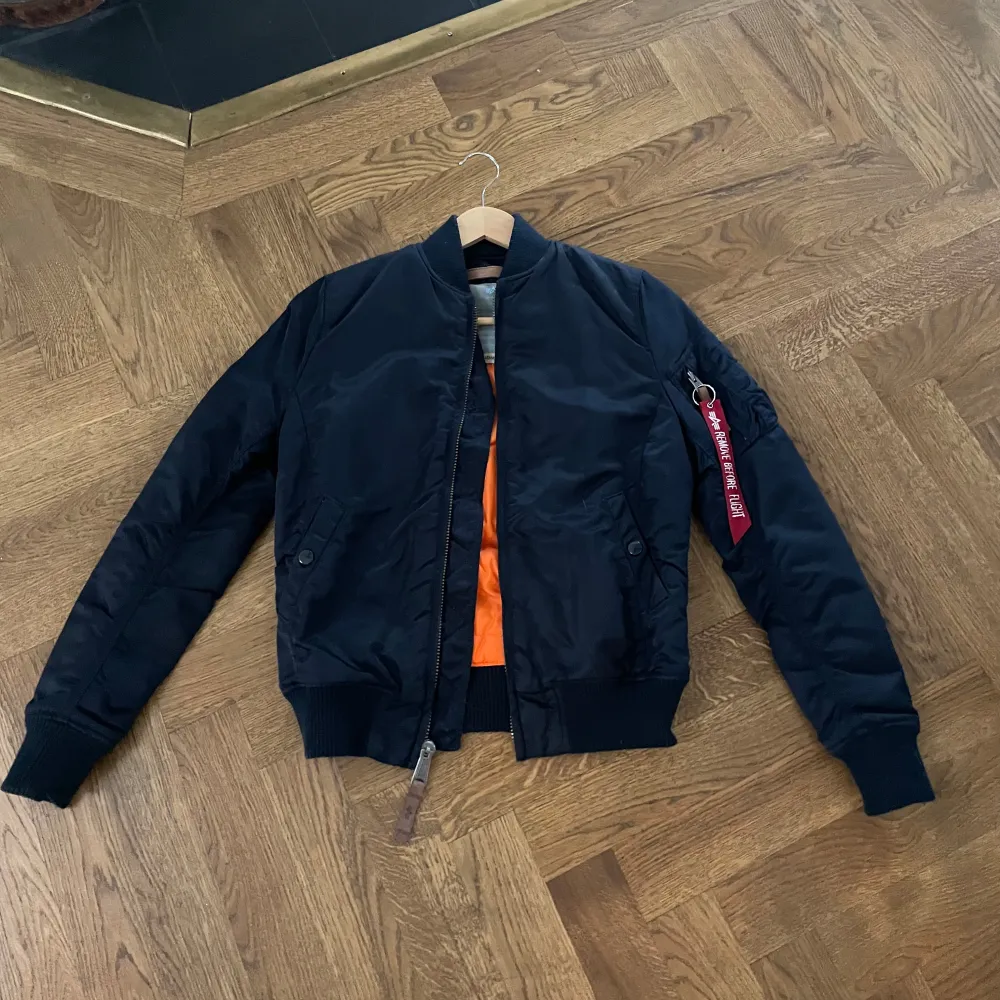 Säljer en snygg marinblå bomberjacka från Alpha Industries i storlek XS för endast 449 kr. Jackan har en cool orange insida och en dragkedja framtill. Perfekt för höst och vår, med ribbade muddar och en klassisk bomberstil. Den är i mycket bra skick och redo för nya äventyr! . Jackor.