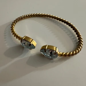 Guldarmband med blå stenar från caroline swedbom.  - Köpt för ca 2 år sedan i fortfarande bra skick! Säljer på grund av ingen användning