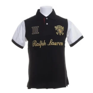 Svart och vit pikétröja från Ralph Lauren - Den har broderade detaljer i guld och en klassisk krage. Storlek M kan passa S