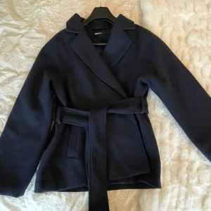 Marinblå kappa från Gina Tricot - Snygg marinblå kappa från Gina Tricot med knytning i midjan. Pris kan diskuteras. 