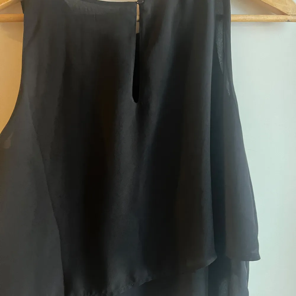 Snygg svart ärmlös klänning från Divided. Perfekt för en stilren look med sin enkla design och lätta material. Klänningen har en diskret dragkedja i ryggen för enkel påklädning.. Puserot.