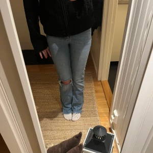 Ljusblå bootcut jeans - Snygga ljusblå jeans med bootcut-stil och slitna detaljer vid knäet. Perfekta för en avslappnad look. De har en klassisk femficksdesign och en bekväm passform.