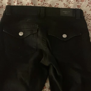 Svarta jeans från Gina Tricot - Snygga svarta jeans från Gina Tricot med en klassisk design. De har silverfärgade knappar och en stilren look. Perfekta för en chic och enkel stil.