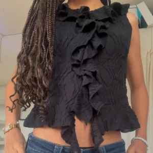 Svart volangtopp - Snygg svart topp med volangdetaljer framtill. Toppen är ärmlös och är från Gina ❣️❣️ Använd 1 gång å har inga tecken på användning. Pris går såklart att diskutera!!