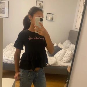 Svart topp med text från Ellos - Snygg svart topp från Ellos med texten 'good vibes only' i rosa. Toppen har korta ärmar och volangdetaljer vid nederkanten. Skriv om ni har frågor eller vill ha flera bilder💕