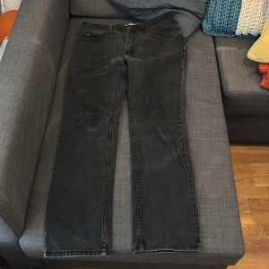 Svarta jeans från Lee - Säljer ett par svarta jeans från Lee i regular fit. De är tillverkade i 100% bomull och har en klassisk design med fem fickor och dragkedja. Perfekta för en avslappnad stil. De är i ett bra skick. Storlek 32/32