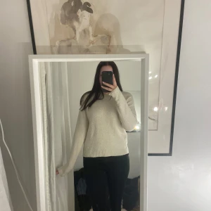 Vit stickad tröja - Säljer en stilren vit stickad tröja med långa ärmar. Perfekt för kyligare dagar och enkel att matcha med olika outfits. Tröjan har en klassisk design med ribbstickade muddar vid ärmslut och nederkant.