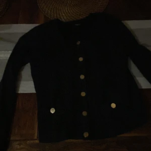 Mörk blå kofta med guldknappar - Elegant mörk blå med guldknappar framtill. Perfekt för en stilren look. Långärmad design som passar bra till både formella och avslappnade tillfällen.