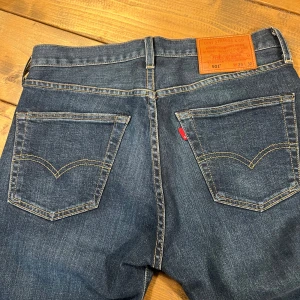 Levis 501 jeans i blå denim - Klassiska Levis 501 jeans i blå denim med normal passform. De har en knappgylf och fem fickor, vilket ger en tidlös look. Perfekta för en avslappnad stil.
