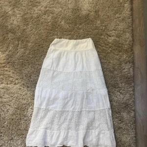 Vit långkjol med spetsdetaljer - Charmig vit långkjol med vackra spetsdetaljer. Perfekt för en somrig look med sin luftiga design och eleganta stil. Jätte fin men har tyvärr inte kommit  till användning för den va lite för kort på mig. pris kan diskuteras 