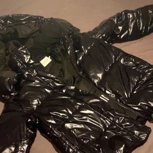 Svart glansig dunjacka från Calvin Klein Jeans - Säljer min svarta, glansiga Calvin Klein-jacka i storlek S eftersom jag inte använder den längre. Den är i väldigt fint skick, både snygg och skön att ha på sig. Hör av dig vid intresse!💕