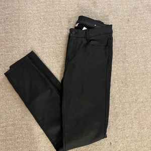 Svarta skinnbyxor  - Snygga svarta skinnbyxor med en klassisk design. De har en rak passform och är perfekta för en stilren look. Byxorna har fickor och knappar framtid. Storlek:L men passar M💗