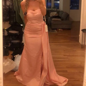 Balklänning  - Jättefin ljusrosa klänning, köpt från JJs house, helt ny, endast provad!! Klänningen är väldigt lång på mig som är 170cm. När man beställde fick man även med genomskinliga band att fästa på en bh. Öppen för prisförslag🎀