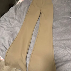 Beige bootcut byxor - Säljer ett par snygga beige bootcut byxor i damstorlek XS. De är perfekta för både vardag och fest med sin stilrena design. Byxorna har en skön passform och är tillverkade i ett mjukt material som ger en bekväm känsla hela dagen.