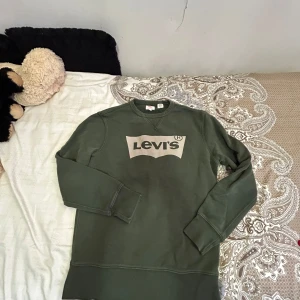 Grön sweatshirt från Levi's - Säljer en snygg grön sweatshirt från Levi's i bra skick. Tröjan har en klassisk passform med långa ärmar och en stor logga på bröstet. Perfekt för en avslappnad stil eller som ett lager under jackan. Passar både höst och vår!