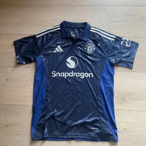 Manchester Uniteds borta tröja - Säljer Manchester Uniteds borta tröja, storlek L men passar även som M, baksidan är tom. Nypris 1 149kr. Tröjan är i helt nytt skick.