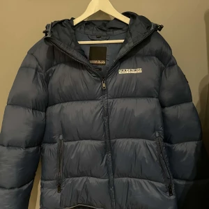 Blå dunjacka från Napapijri - Säljer en blå dunjacka från Napapijri i regular fit. Använd fåtal gånger, väldigt bra skick. Nypris ca 2000kr. Pris kan diskuteras!