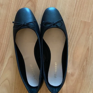 Svarta ballerinaskor - Säljer ett par klassiska svarta ballerinaskor från Primark i bra skick. De har en söt liten rosett på tån och är perfekta för både vardag och fest. Skorna är bekväma och lätta att matcha med olika outfits. Köpte i Tyskland men d va lite för stora🥰