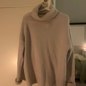 Beige stickad polotröja från 157 - Mysig beige/rosa stickad polotröja från 157 i storlek S. Har en hög krage och långa ärmar. Tröjan har en avslappnad passform och ribbade muddar vid ärmslut och nederkant. Använd fåtal gånger