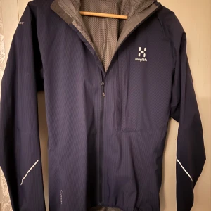 Mörkblå vindjacka från Haglöfs - Säljer en mörkblå vindjacka från Haglöfs i mycket bra skick då den inte kommer till användning. Jackan är i storlek S