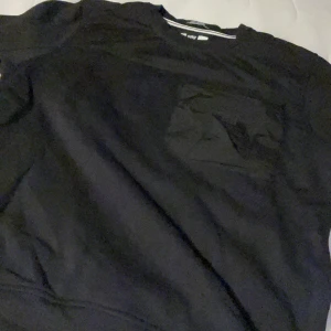 Svart tröja från Weekend Offender - Säljer en svart tröja från Weekend Offender i bra skick. Den har en cool ficka på bröstet och en stilren design. Perfekt för vardagsbruk eller en avslappnad utekväll. Storleken är M och materialet känns mjukt och bekvämt. Ordinare pris 1000kr