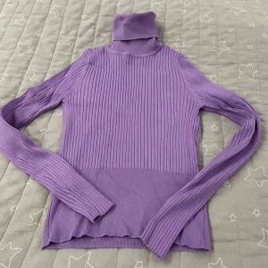 Lila ribbad polotröja - Säljer en snygg lila polotröja i ribbat material köpte från Zara. Perfekt för kyliga dagar med sin höga krage och långa ärmar. Tröjan är både stilren och bekväm, idealisk för höst och vinter. Passar bra till både jeans och kjol!. Anans bara en gång och är i mycket bra skick! 