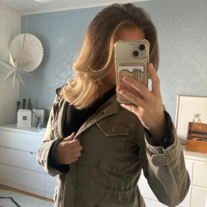 Olivgrön jacka från Hunkydory - Säljer en snygg olivgrön jacka från Hunkydory. Perfekt för höst och vår med sin lätta och bekväma passform. Jackan har långa ärmar och en dragkedja framtill. Den är i bra skick och redo för nya äventyr. Passar perfekt till vardagsoutfiten!