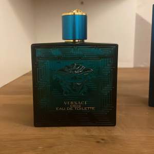 Säljer en flaska Versace Eros Eau de Toilette, 100 ml. Flaskan är i en snygg turkos färg med ett elegant mönster och har en gyllene detalj på korken. Perfekt för den som vill ha en fräsch och maskulin doft. Flaskan är nästan full och kommer med originalförpackning.