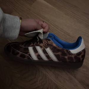 Adidas Samba leopard - Säljer ett par unika Adidas sneakers i leopardmönster med vita detaljer och blå insida. Är i mycket bra skick. Perfekta för att sticka ut i mängden och ge din outfit en cool touch🐆