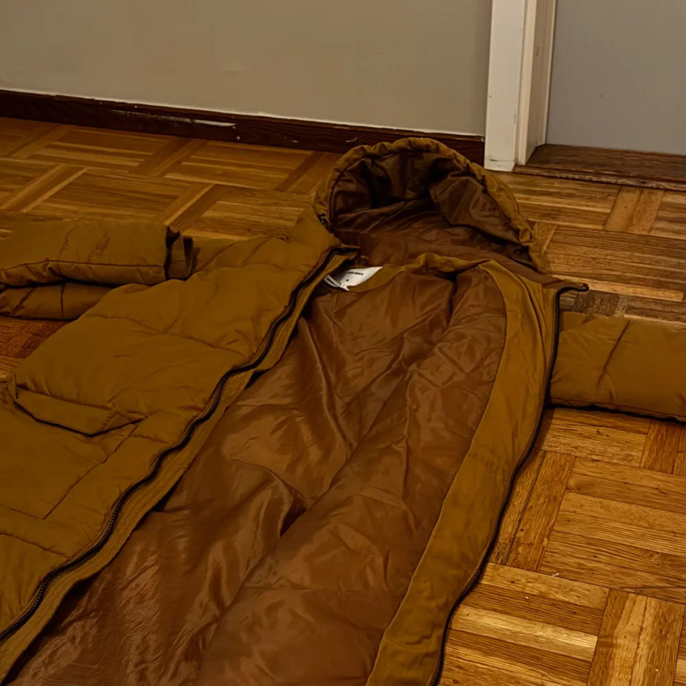 Säljer en brun lång pufferjacka i mycket bra skick. Den har en dragkedja framtill och två stora fickor. Perfekt för kalla vinterdagar med sin varma vaddering och huva. Endast: 599. Takit.