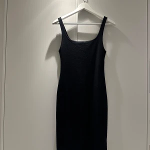 Svart klänning från Zara - Snygg svart klänning från Zara i ett enkelt och stilrent snitt. Den är ärmlös och har en tight passform som framhäver figuren. Perfekt för både vardag och festliga tillfällen. Tillverkad i ett bekvämt material som sitter skönt mot kroppen.