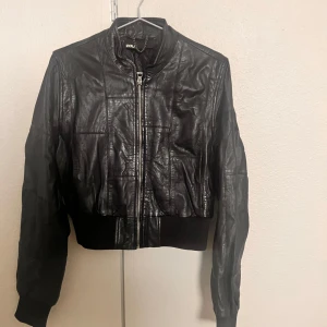 Läderjacka från Zoul - Snygg svart läderjacka från Zoul i mycket bra skick. (Äkta läder) Jackan har en dragkedja framtill och ribbade muddar vid ärmslut och nederkant. Perfekt för höst och vår:)