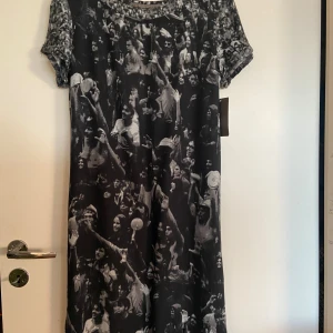 Svartvit klänning med fototryck - Unik svartvit klänning med ett coolt fototryck av vad ser ut som publik på en konsert.Klänningen har korta ärmar. Oanvänd med prislapp