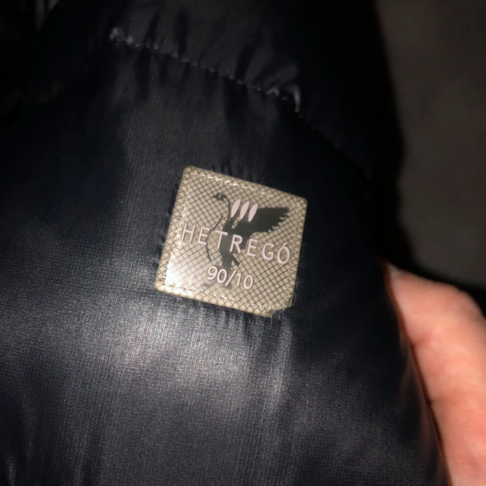 Säljer en snygg svart dunjacka från Hetregó i mycket bra skick. Jackan är perfekt för vintern med sitt varma dunfoder och har en praktisk huva. Den har dragkedja framtill och två fickor med knappar på bröstet. Perfekt för kalla dagar! Skriv privat om frågor. . Takit.