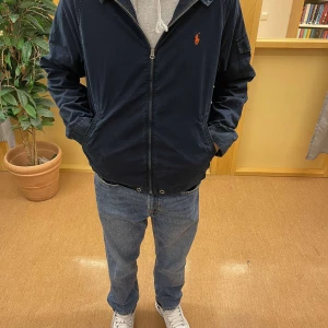 Mörkblå Ralph Lauren jacka - Vi säljer just nu en mörklblå vindjacka som är perfekt till hösten. Skicket är 10/10, inprincip helt ny. Storlek L men sitter som M. Startpris 599kr, vid snabb affär kan vi diskutera pris!