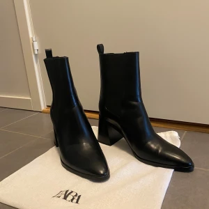 Svarta boots från Zara - zara svarta stövlar. de är nya, jag har aldrig använt dem och de är i perfekt skick, stövlarna är i storlek 39 .Perfekta för höst och vinter, dessa boots har en stilren design som passar både till vardags och fest. De är i mycket bra skick och kommer med en praktisk förvaringspåse.