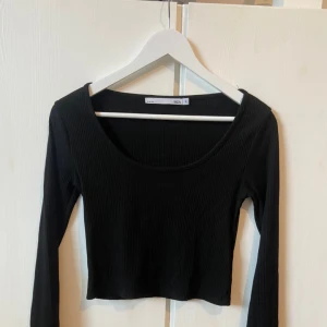 Svart ribbad croppad topp - Säljer en svart ribbad croppad topp från lager157 i storlek S. Den har en snygg, tight passform och långa ärmar, perfekt för både vardag och fest. Toppen är i mycket bra skick och passar utmärkt till höst- och våroutfits.